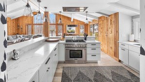 A modern kitchen with a large island, stainless steel appliances, and wooden accents. - Ski-In/Out Lodge | Stratton Mountain (Stratton)