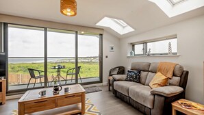 A modern living room with a large window, a sofa, a coffee table, and a TV. - 2 Bed in Sheringham (oc-b27372) (Sheringham)