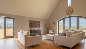 Un soggiorno spazioso con soffitto alto, ampie finestre e vista sulla campagna.