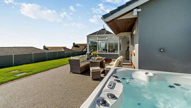 Een hottub, buitenzitplaatsen en een terras met glazen wanden.