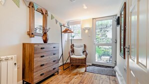 A room with a wooden dresser, a wicker chair, and a large window. - 1 Bed in Mevagissey (oc-h27460) (Mevagissey)