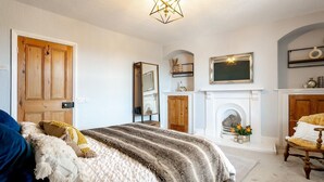 Quarto com cama, lareira, espelho e lustre.