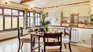 A dining area with a wooden table, chairs, and a view of the outside through large windows.