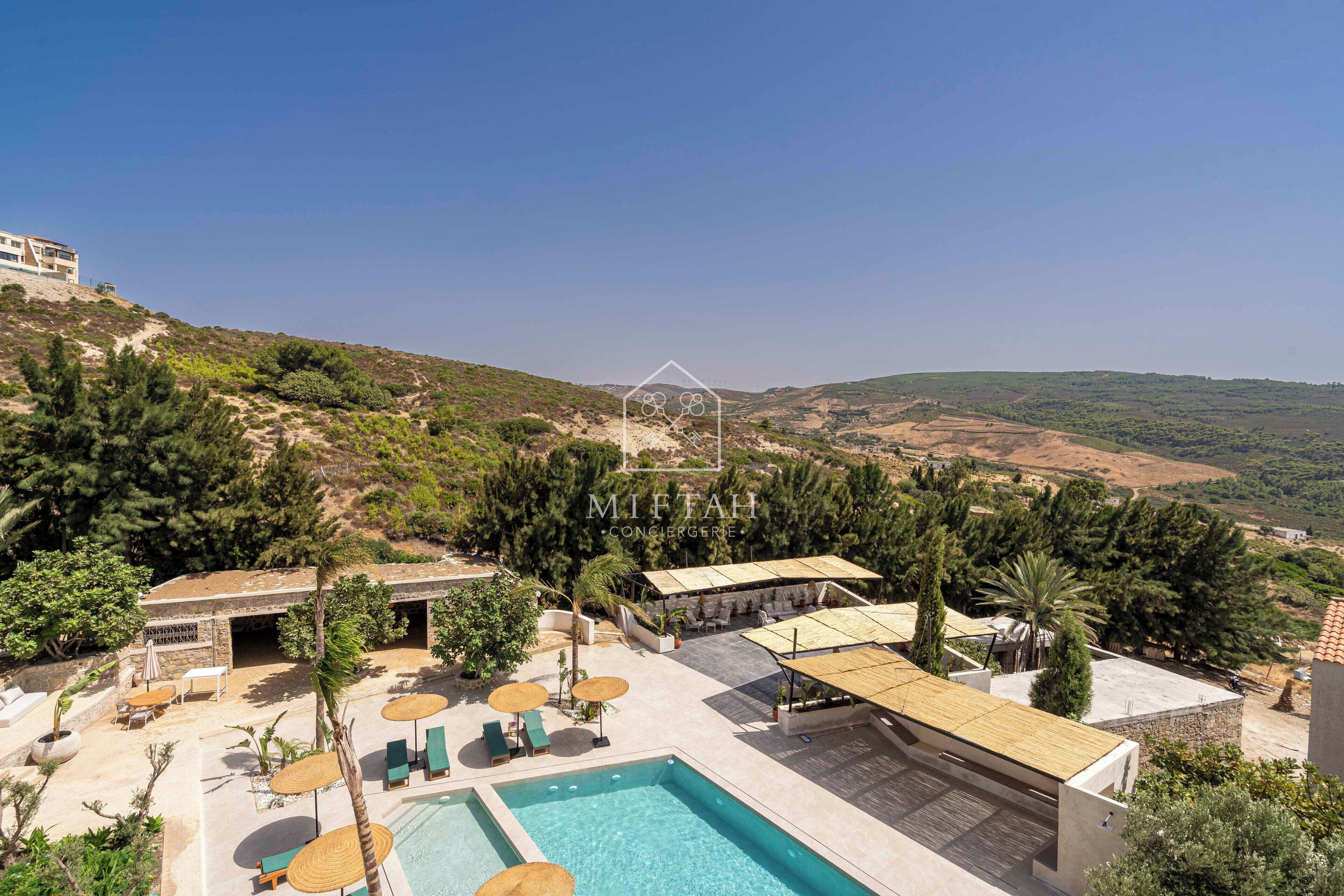 Un complexe hôtelier doté d’une piscine, d’un espace extérieur aménagé et offrant une vue sur les collines environnantes.