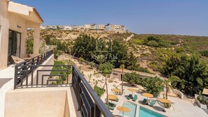 Um hotel com área de piscina, mobiliário de exterior e vista para outros edifícios numa encosta.