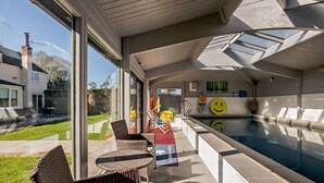 An indoor swimming pool with a glass wall, wicker furniture, and a smiley face decoration. - 2 Bed in Bale (oc-v27448) (Bale)