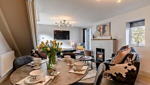 A modern living room with a fireplace, a dining area with tulips, and a cozy seating arrangement. - 2 Bed in Bale (oc-v27448) (Bale)