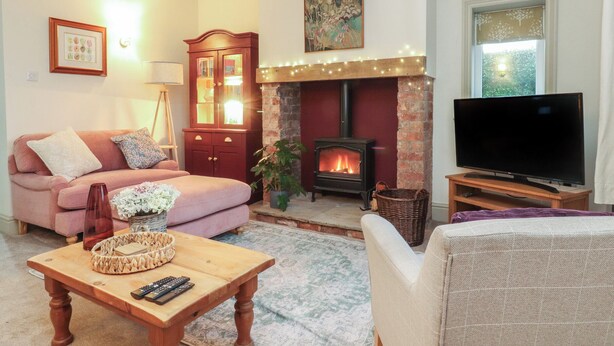 Un salon chaleureux avec une cheminée, un canapé, un téléviseur et une table basse en bois.