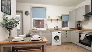 Une cuisine compacte équipée d’un lave-linge, d’un four et d’un coin repas avec une banquette.