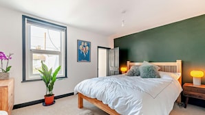 Ein Schlafzimmer mit Bett, Fenster, Tür, Nachttisch und Lampe.