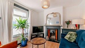 Ein Wohnzimmer mit Kamin, Fernseher, Sofa, Couchtisch und einem großen Spiegel.
