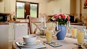 Une table à manger dressée avec des assiettes, des bols, des verres à vin et un vase rempli de fleurs.