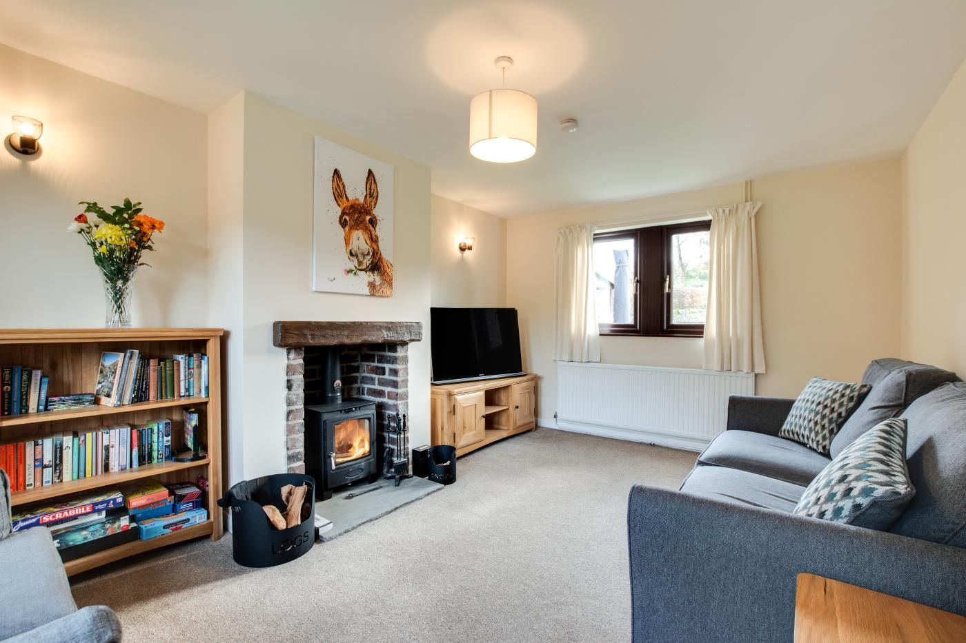 Una sala acogedora con chimenea, una estantería, un sofá y una televisión.