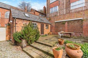 A brick house with a small garden, a wooden bench, and a table. - 1 Bed in Whitby (oc-d27454) (Whitby)