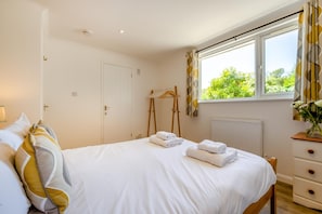 A bedroom with a bed, a dresser, a radiator, and a window with curtains. - 4 Bed in St. Levan (oc-b27515) (Saint Levan)