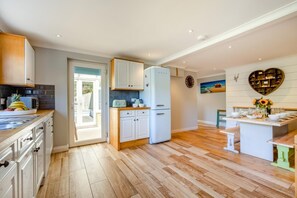 A modern kitchen with a central island, white cabinetry, and a view to the outside. - 4 Bed in St. Levan (oc-b27515) (Saint Levan)