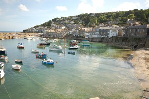 Une ville côtière avec des bateaux amarrés dans un port, des maisons le long de la côte et une colline en arrière-plan.