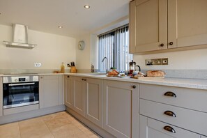 A modern kitchen with a built-in oven, a sink, and a window with blinds. - 2 Bed in Letheringsett (oc-c27516) (Letheringsett)