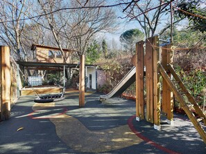 Un parque infantil con tobogán, columpios y una estructura para escalar.