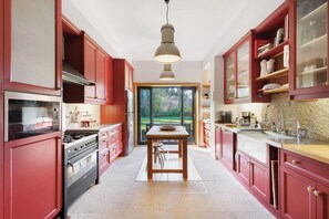Una cocina moderna con armarios rojos, una isla central y vistas a través de la puerta de vidrio.