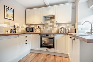 A compact kitchen with white cabinets, a microwave, an oven, and a sink. - 2 Bed in Weybourne (oc-h27517) (Weybourne)