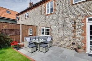 A stone house with a patio, outdoor furniture, and a wooden fence. - 2 Bed in Weybourne (oc-h27517) (Weybourne)