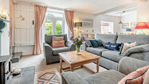 Un salon chaleureux avec une cheminée, un canapé, une table basse et une vue sur l’extérieur.