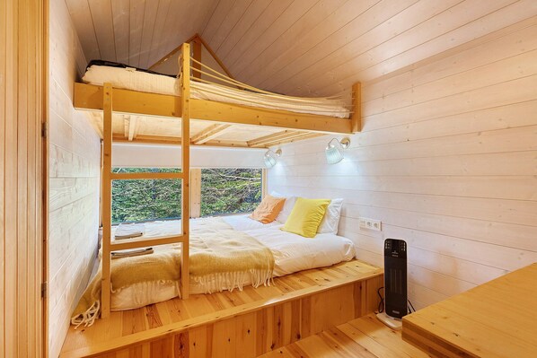 A bunk bed with a wooden headboard, a bedside table, a lamp, and a power outlet.