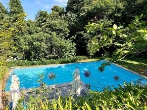 A swimming pool surrounded by lush greenery and a white umbrella. - Chalet 'Lushana' with Mountain View, Private Terrace and Shared Garden (Ponte de Lima)