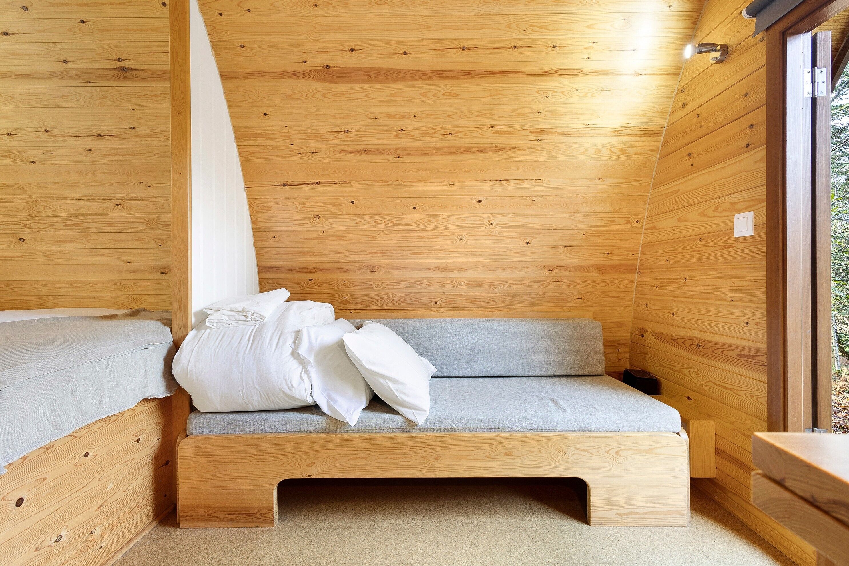 Un interior de madera con una cama, un banco y una ventana.