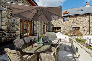 A stone building with a patio area featuring wicker furniture and a table with a glass top. - 3 Bed in Okehampton (oc-h27530) (South Tawton)