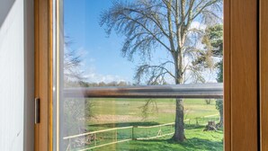 A view through a glass door with a metal railing, leading to a grassy outdoor area with trees and a fence. - 2 Bed in Eccles (oc-l27507) (Eccles)