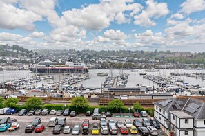 Eine Marina mit Booten, ein großes Kreuzfahrtschiff und ein Parkplatz mit Autos.