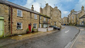 A stone-built street with traditional houses, a parked car, and a clear sky. - 3 Bed in Hawes (oc-hhmy23) (Hawes)