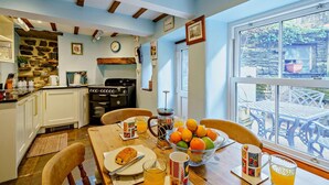 A cozy kitchen with a stone wall, wooden beams, and a dining area with a table set for breakfast. - 3 Bed in Hawes (oc-hhmy23) (Hawes)