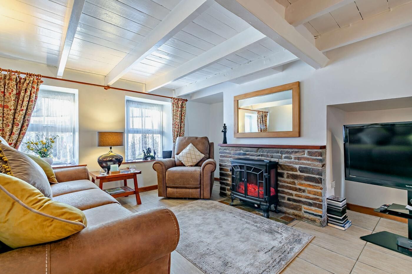 A cozy living room with a fireplace, a sofa set, and a television.