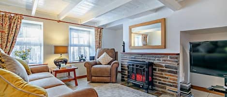 A cozy living room with a fireplace, a sofa set, and a television.