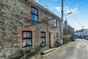 A stone building with a traditional design, featuring a small porch and a single visible door. - 3 Bed in St. Issey (oc-v27518) (Saint Issey)