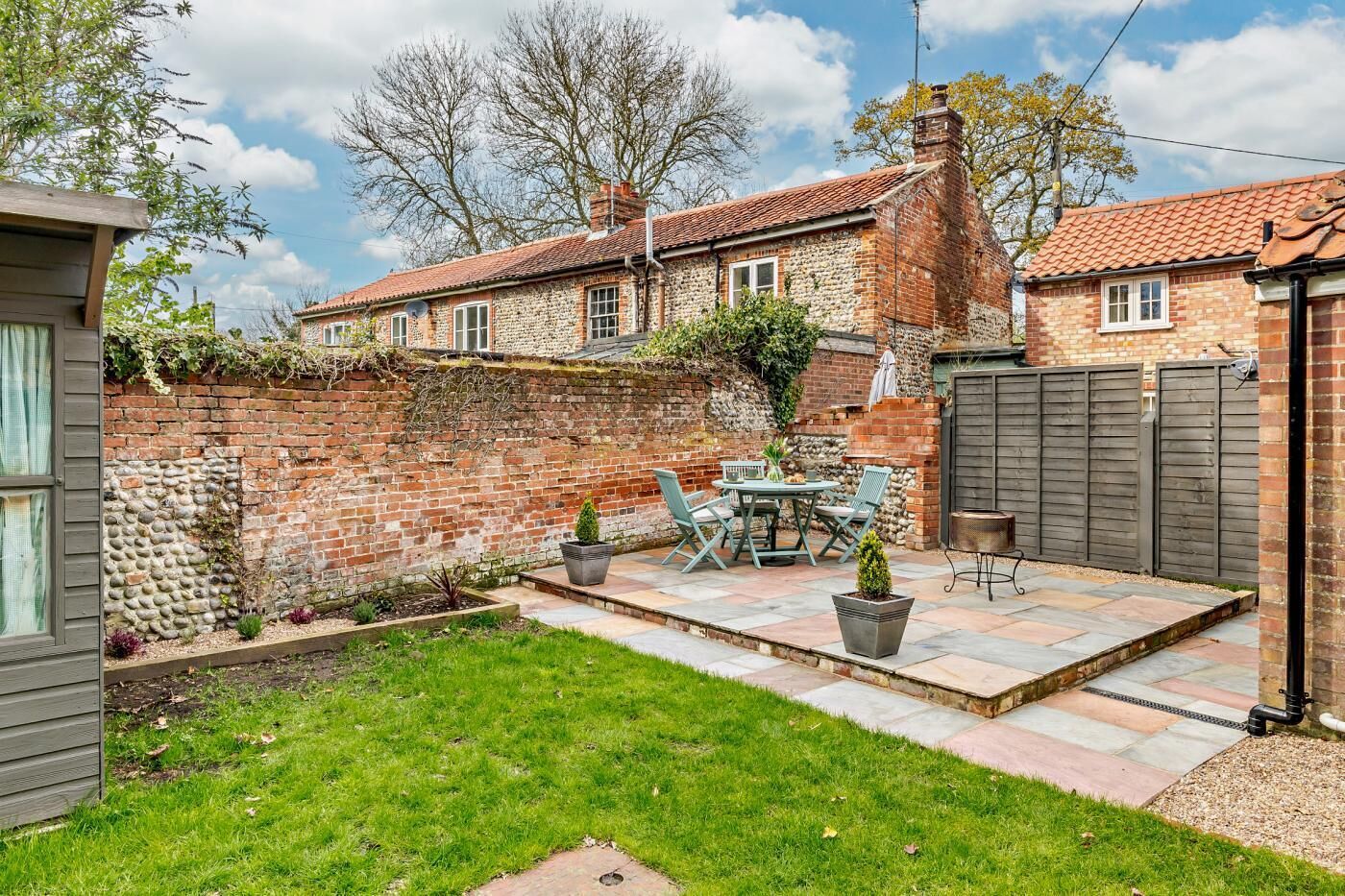 A backyard with a patio, a brick wall, and a garden.