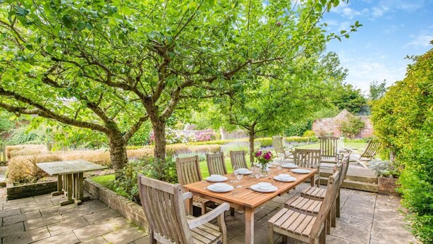 Een terras met een houten tafel voor zes personen, omringd door houten stoelen.