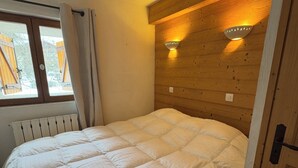 A bedroom with a wooden headboard, a large bed, and two wall-mounted lights.