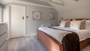 Ein Schlafzimmer mit einem großen Bett, einer weißen Tür und zwei Wandbildern.