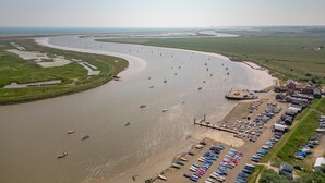 Eine Luftaufnahme eines Küstenhafens mit angestaubten Booten und einem Sandstrand.