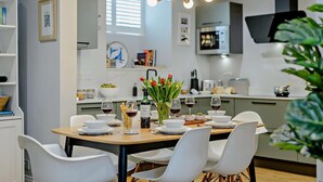 A modern dining area with a wooden table set for four, white chairs, and a vase of red tulips. - 3 Bed in Ruswarp (oc-wa264) (Ruswarp)