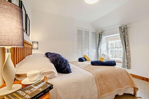 A neatly arranged hotel room with a bed, bedside table, lamp, and a window with curtains. - 2 Bed in St. Minver (oc-p27580) (Saint Minver)