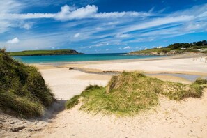 A beach with clear skies, a sandy shore, and grassy dunes. - 2 Bed in St. Minver (oc-p27580) (Saint Minver)