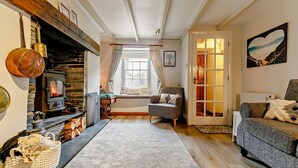 Un salon chaleureux avec une cheminée en pierre, un canapé confortable et une fenêtre agrémentée de rideaux.