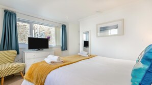 Une chambre d’hôtel avec un lit, une télévision, une chaise et une fenêtre avec des rideaux.