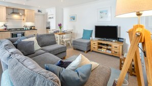 Un salon moderne avec un canapé gris, un téléviseur et un meuble en bois.