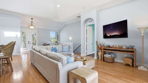 Un salón amplio con un sofá, una mesa de centro y un televisor montado en la pared.